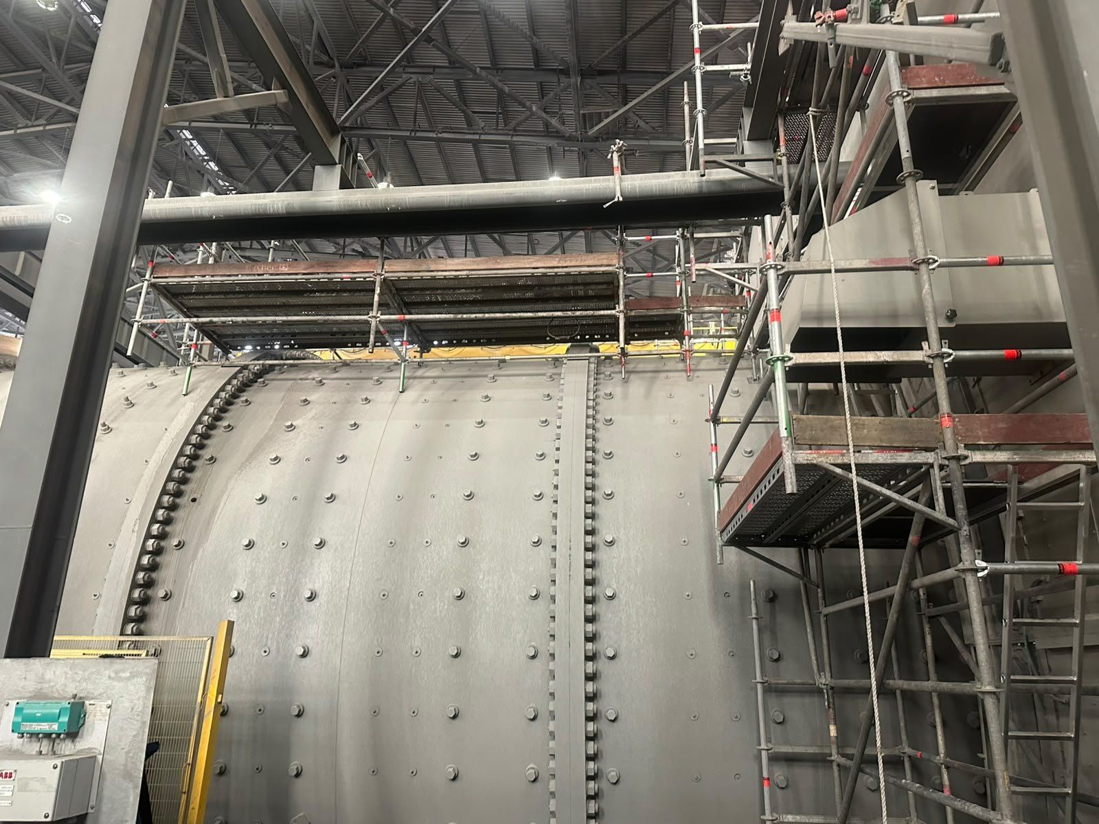 Pasarela de andamio montada bajo vigas de acero en una nave industrial